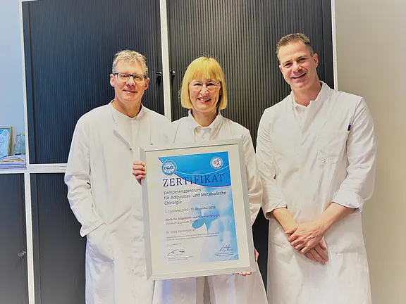 Bild mit Urkunde. Dr. Karin Hüttner, Ärztliche Leiterin des Adipositaszentrums, Dr. Oliver Ponsel, Direktor der Klinik für Allgemein- und Viszeralchirurgie und Oberarzt Dr. (Univ. Niš) Filip Kostic