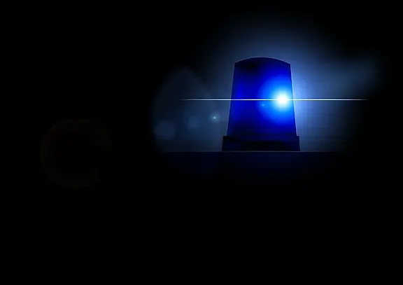 Ein blauer Polizeihorn mit leuchtendem Licht steht im Dunkeln. Der Hintergrund ist schwarz, wodurch das Licht des Horns stark hervorsticht. Die Szene vermittelt ein Gefühl von Dringlichkeit und Alarmbereitschaft.