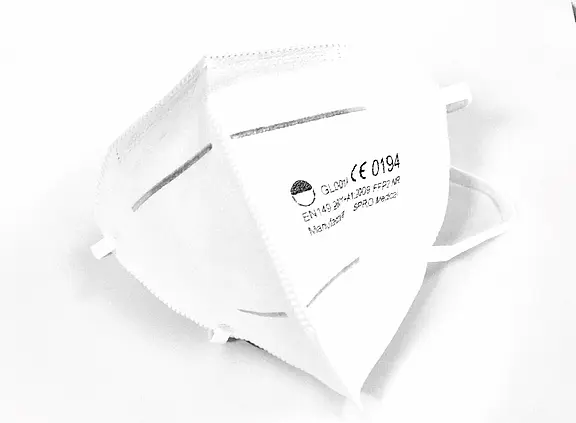 Weiße FFP2-Atemschutzmaske mit Ohrschlaufen in Nahaufnahme. Die Maske zeigt CE-Kennzeichnung und Modellangaben; gefaltetes Design mit Nasenbügel, geeignet zum Schutz vor Aerosolen und Staub.