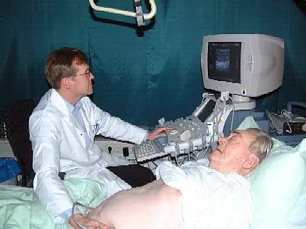 Blutfluss-Messung in einer Transplantatniere Ein Arzt führt bei einem älteren Patienten eine Ultraschalluntersuchung des Bauchs durch. Der Patient liegt auf einer Liege, der Arzt setzt den Schallkopf an, und auf dem Monitor ist das Bild der Untersuchung zu sehen.