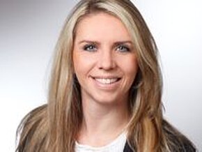 Das Bild zeigt eine lächelnde Frau mit langen, blonden Haaren. Sie trägt ein helles Oberteil und hat einen freundlichen Ausdruck im Gesicht. Der Hintergrund ist neutral und hell.