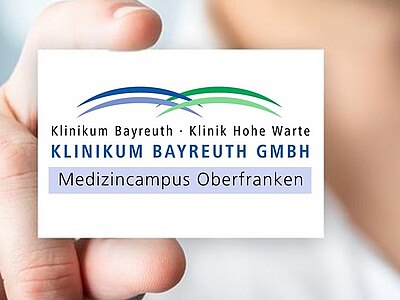 Logo des Klinikum Bayreuth GmbH mit der Aufschrift: „Klinikum Bayreuth · Klinik Hohe Warte“, darunter „KLINIKUM BAYREUTH GMBH“ und „Medizincampus Oberfranken“. Zwei geschwungene blaue und grüne Linien darüber.