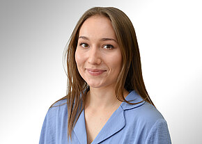 Selina Hasenöhrl Porträtfoto: Eine junge Frau mit langem braunem Haar lächelt freundlich. Sie trägt ein hellblaues Oberteil mit Kragen. Neutraler, heller Hintergrund; Fokus auf freundlichem Ausdruck und professionellem Erscheinungsbild.