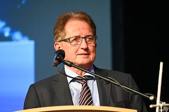 Mann mit Brille in Anzug und gestreifter Krawatte spricht am Rednerpult in einem Saal. Er steht hinter einem Mikrofon, Blick nach vorn. Bühne und neutraler Hintergrund, Fokus auf die Rede.